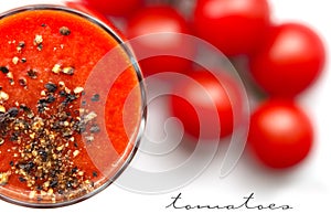 Glass cup with tomato juice with ground black pepper and cherry tomatoes on white background. top view