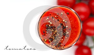 Glass cup with tomato juice with ground black pepper and cherry tomatoes on white background. top view