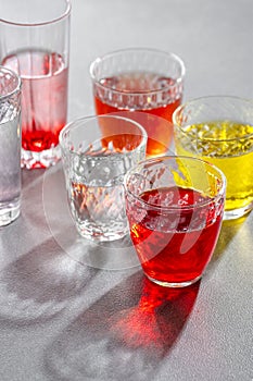 Glass cups with colorful cold drinks on a gray stone table. Shooting with hard light