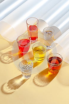Glass cups with multi-colored cold drinks on a yellow background. Shooting with hard light