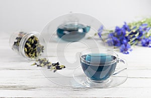 glass cups and teapot of Butterfly pea tea. Anchan  clitoria ternatea on a white marble background. with bouquet of blue flowers