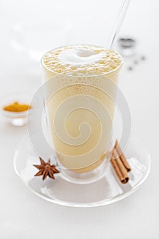 A glass of curcuma latte with glass tube on white table closeup