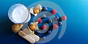 Glass of dairy product,on blue background with raspberries, blueberries, physalis,two cookies.Concept of healthy diet photo