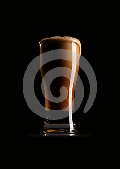 A glass of dark beer on a black background.