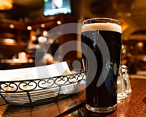 Glass of dark beer on a table in a pub setting