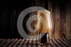 A glass of dark beer on wooden background. Stout in bar.