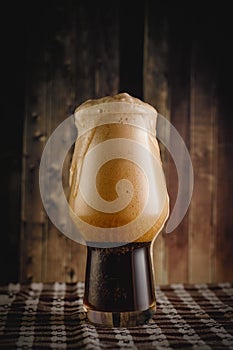 A glass of dark beer on wooden background. Stout in bar.