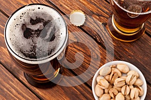 glass of dark cold frothy beer, nuts, bottle cap, old wooden tab