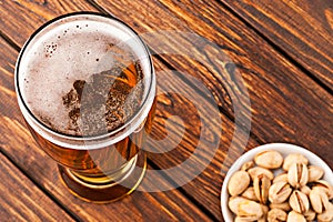 glass of dark cold frothy beer, nuts old wooden table