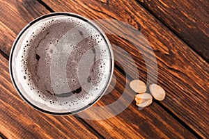 glass of dark cold frothy beer, nuts old wooden table