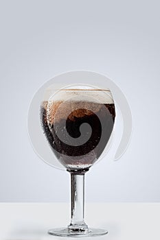 Glass of dark foamy beer isolated over gray background. Concept of alcohol drinks, party