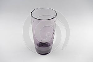 Glass of dark glass with drops of water on a white background.