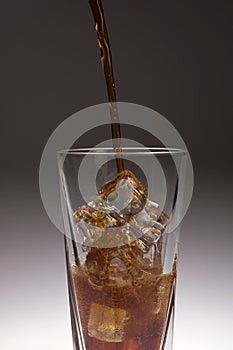 Glass with dark soda bring poured over ice