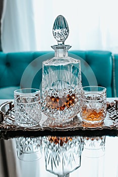 Glass decanter with alcohol and two glasses on a light background of the bar