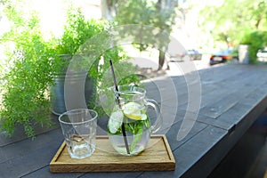 Glass decanter and glass faceted cup stands on plank on table in