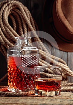 Glass and decanter with a strong alcoholic drink on an old wooden table