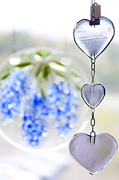 Glass decorations in shape of hearts and flowers is hanging in a window