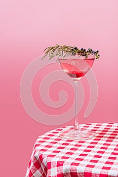 Glass of delicious alcohol drink with berries, cosmopolitan cocktail on checkered tablecloth isolated over peach