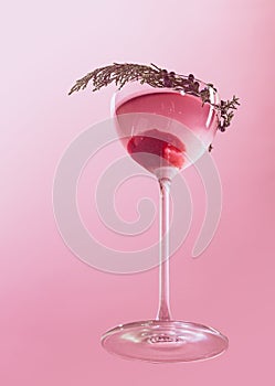 Glass of delicious alcohol drink with berries, cosmopolitan cocktail isolated over pink background