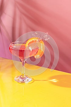 Glass of delicious alcoholic cocktail with rose water and sparkling wine isolated over pink yellow background