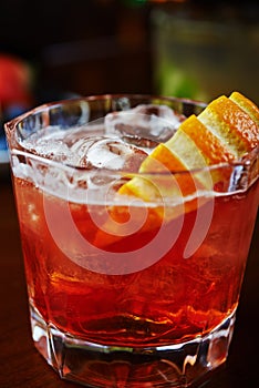 Glass of delicious alcoholic whiskey cocktail or lemonade with ice and a slice of orange on a table in a bar or restaurant with de