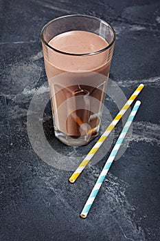 Glass of delicious cold chocolate milk with cocktail straw