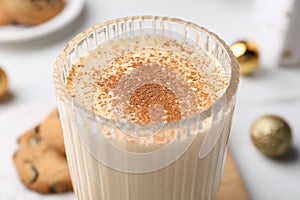 Glass of delicious eggnog with cinnamon on table, closeup