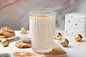 Glass of delicious eggnog with cinnamon on white table