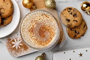 Glass of delicious eggnog with cinnamon on white table, flat lay