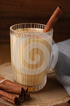 Glass of delicious eggnog with cinnamon on wooden table