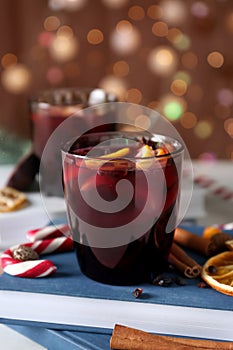 Glass of delicious mulled wine on books against blurred lights