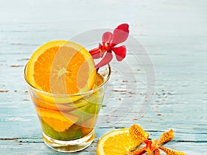 Glass delicious refreshing drink of mix fruits orange and lemon on blue wooden, infusion water