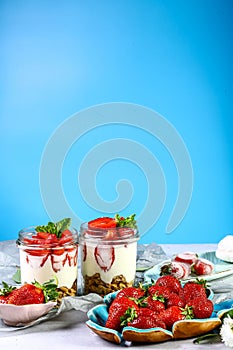 Glass dessert with strawberries and cream Isolated on a blue background. Copy space. Healthy homemade dessert