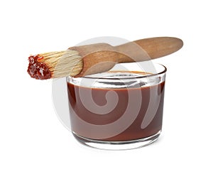 Glass dish of barbecue sauce with basting brush on white