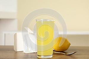 Glass with dissolved drug and box of medicine sachets on wooden table indoors