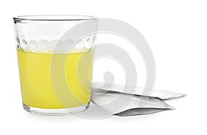 Glass of dissolved medicine and sachets on white background