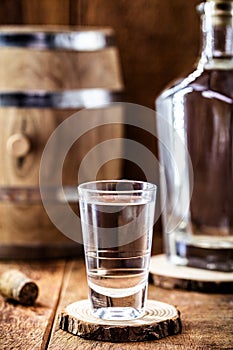 Glass of distilled drink, strong alcoholic drink, detail image of pub, bar, with old oak barrel in the background