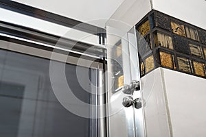 Glass door with a chrome handle in the bathroom, which is lined with decorative ceramic tiles.