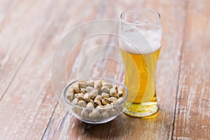 Glass of draught beer and pistachio nuts on table