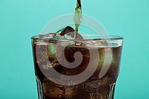 A glass with a drink on a blue background. A glass of cola and ice