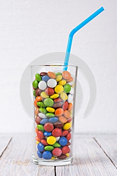 A glass with a drink on the table. Transparent glass with a multi-colored dragee.