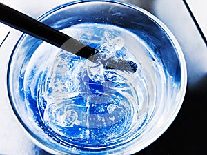 A glass of drinking water filled with ice on the wooden table