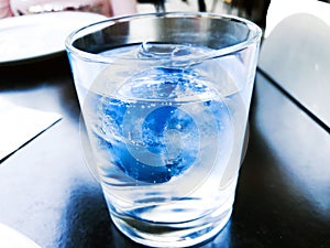 A glass of drinking water filled with ice on the wooden table