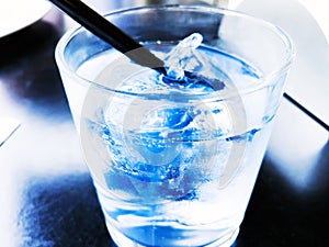 A glass of drinking water filled with ice on the wooden table