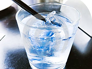 A glass of drinking water filled with ice on the wooden table