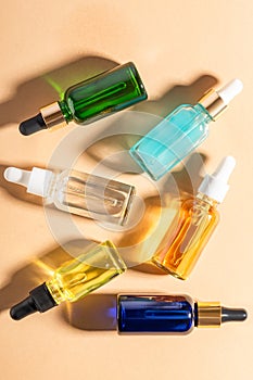 glass dropper bottles with beauty oils or serum on beige background. Skincare products with beautiful daylight. Trending concept