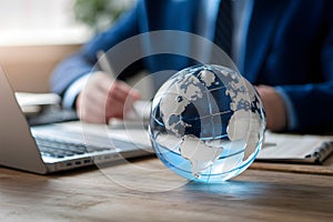 Glass earth on desk in business concept photo, representing global commerce and corporate responsibility