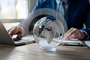 Glass earth on desk in business concept photo, representing global commerce and corporate responsibility