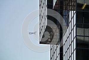 Glass facade detail of modern building and airplane on the sky in the background