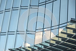 Glass facade of an office building with reflections of the blue sky and clouds